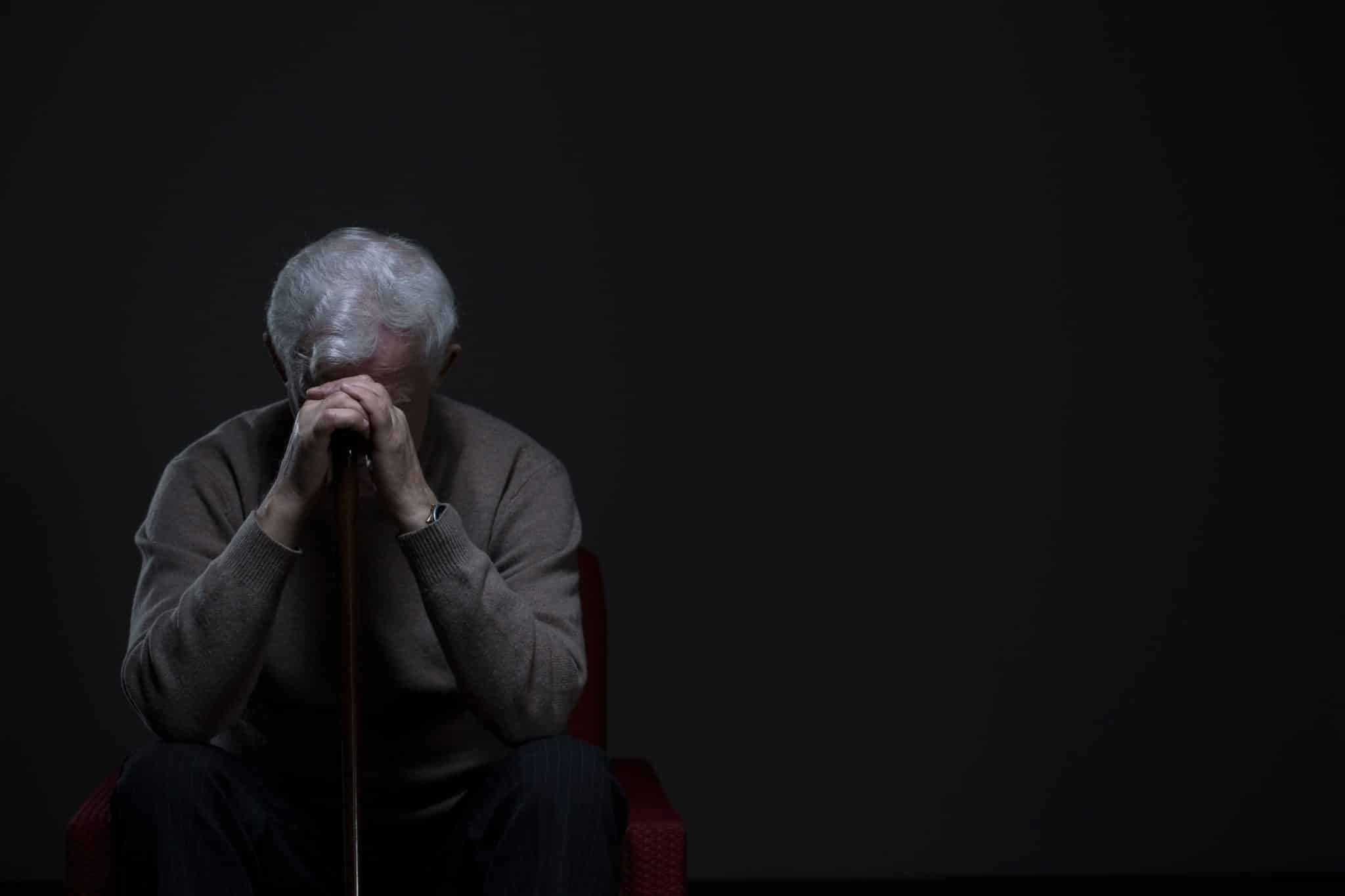 Older Man in Dark with Head in His Hands