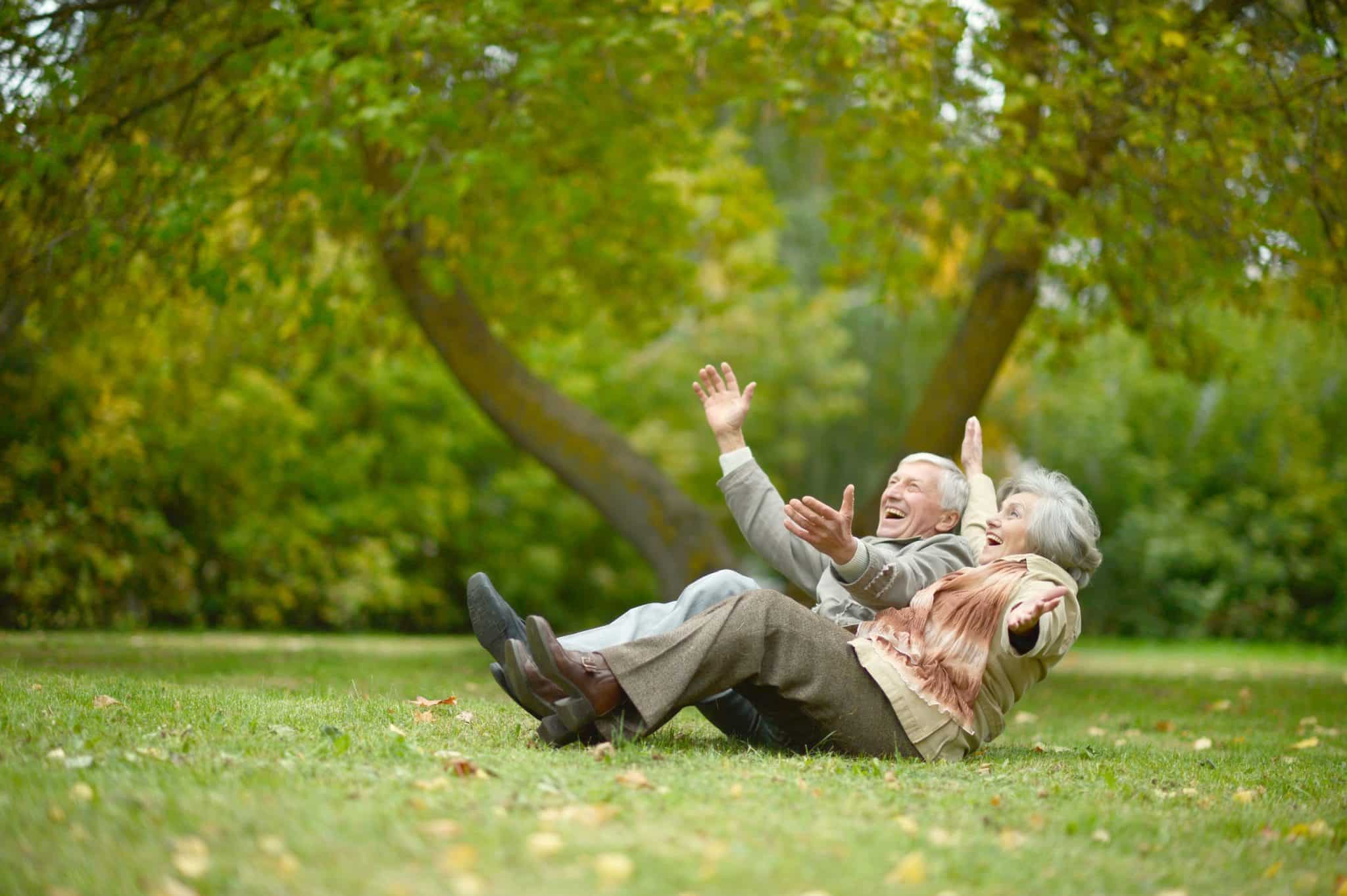 Elderly Couple Playing and Laughing on the Ground at the Park