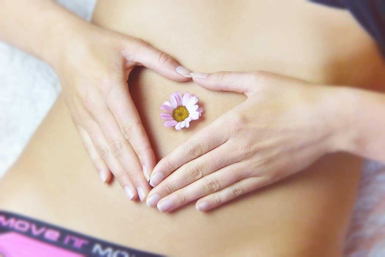 Patient making heart with hands over belly button filled with a small flower