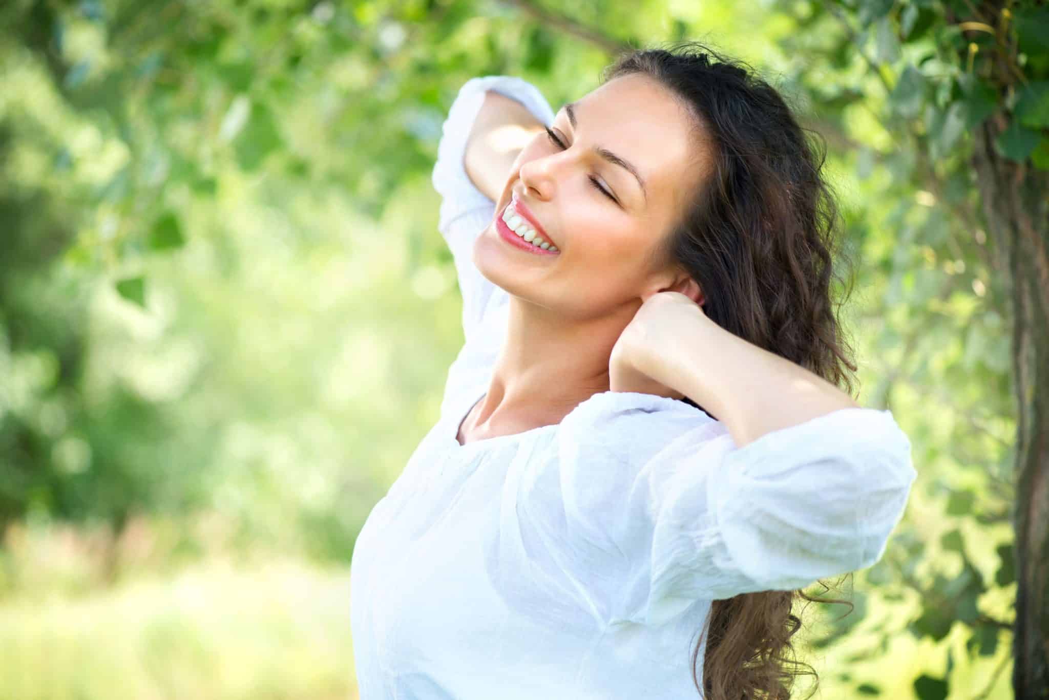 Woman Feeling Great from IV Vitamin Therapy Benefits While Smiling and Stretching Outdoors