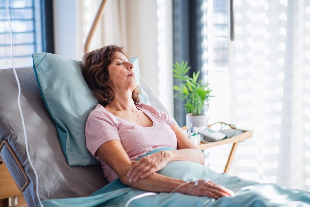 Middle Aged Female Patient Leaning Back on Bed Receiving IV Treatment