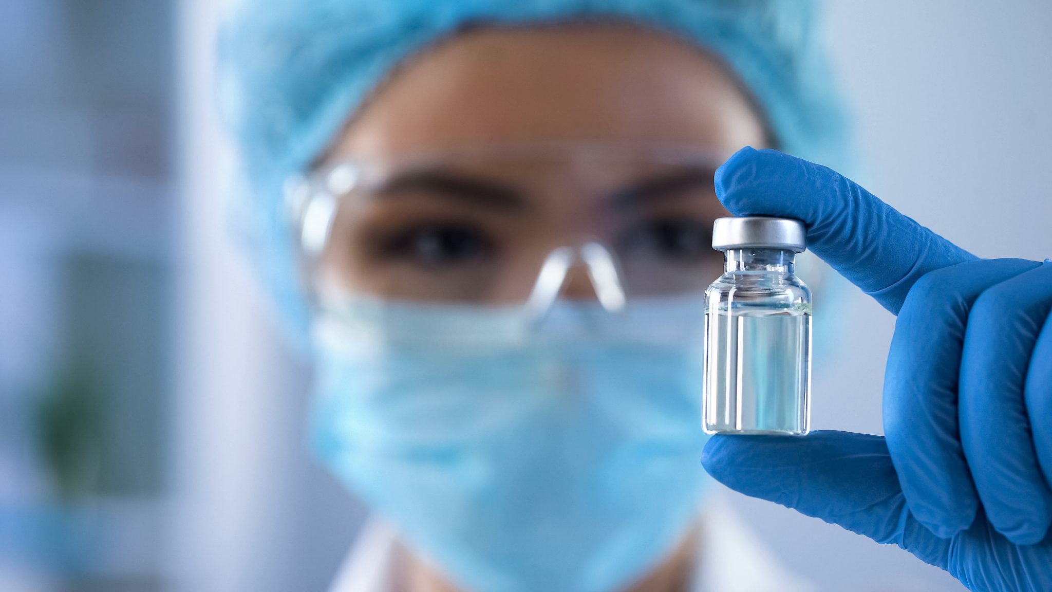 Close-up of a healthcare professional in a laboratory setting holding a vial of compounded GLP-1 medication.