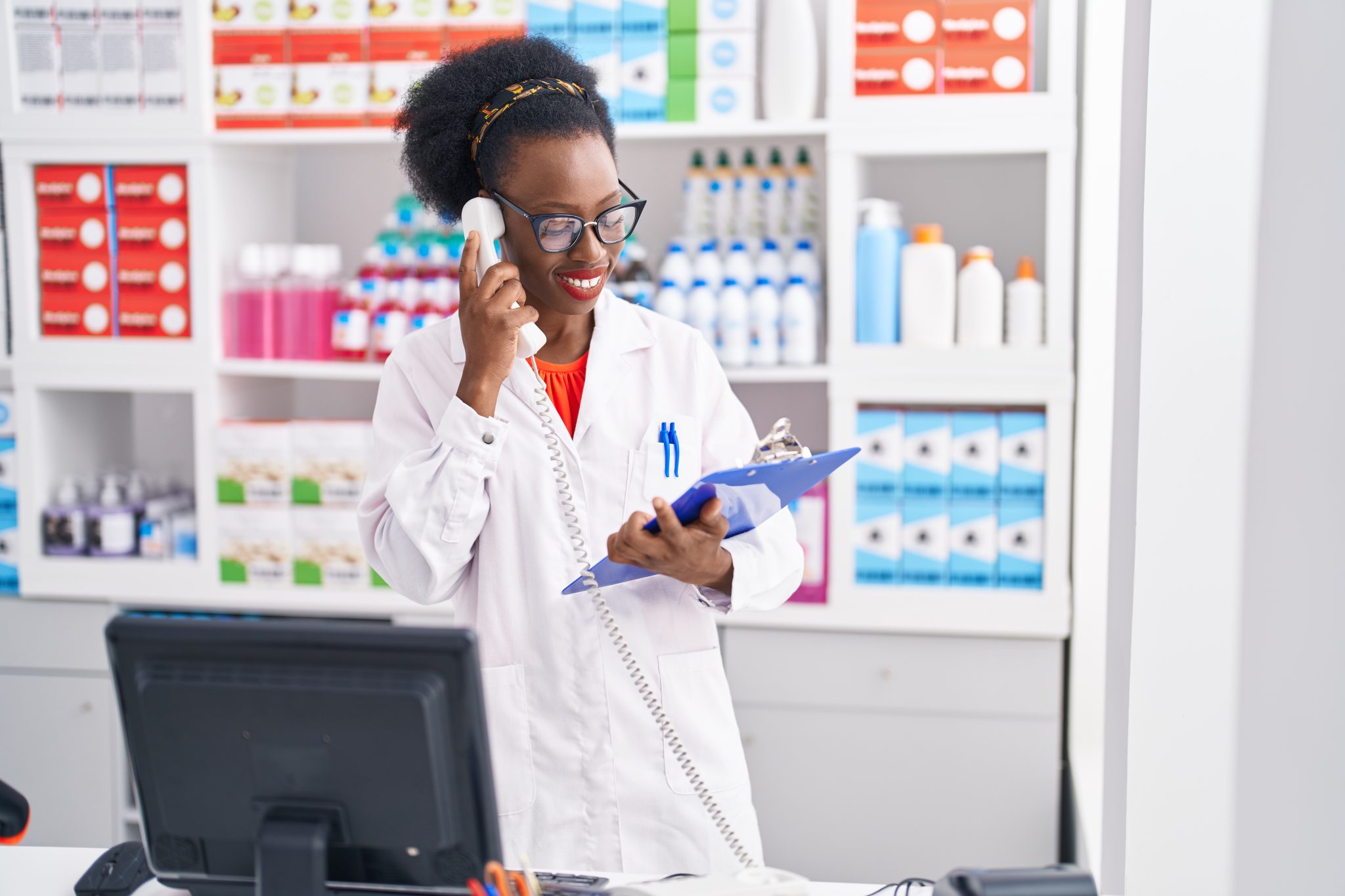 A pharmacist engaging in a consultation over the phone while referencing a clipboard.